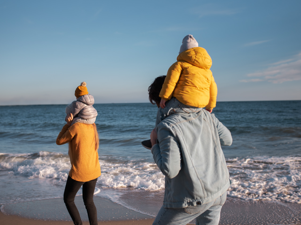 Familie am Strand der Ostsee zur Nebensaison in warmer Kleidung direkt am Meer